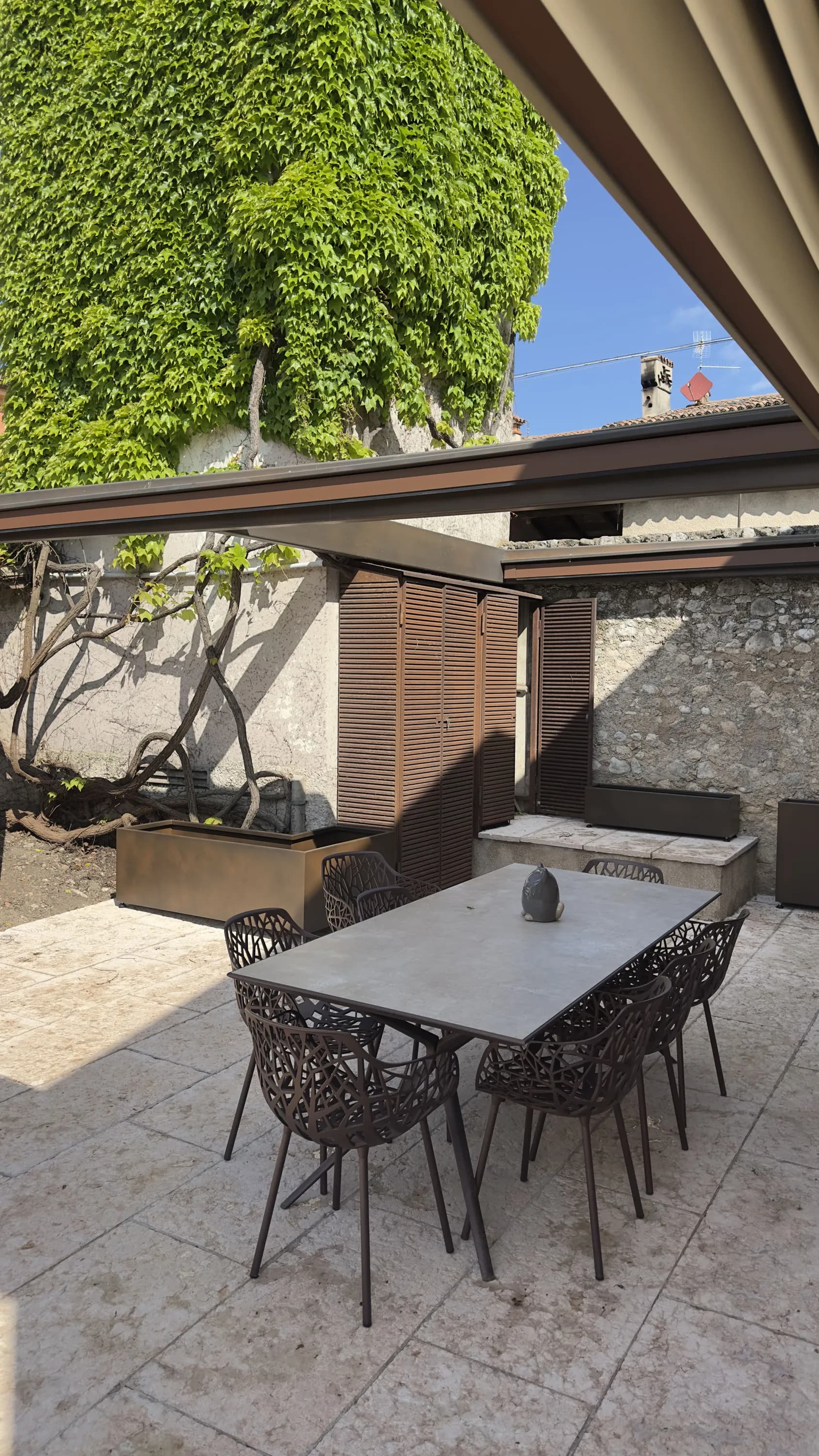 Area pranzo sotto pergola corten con fioriera in ferro su misura